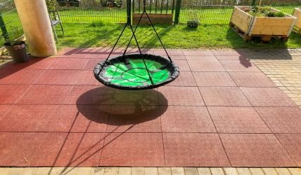 Monteret røde gummifliser under sansegynge hos Bifrost i Børkop